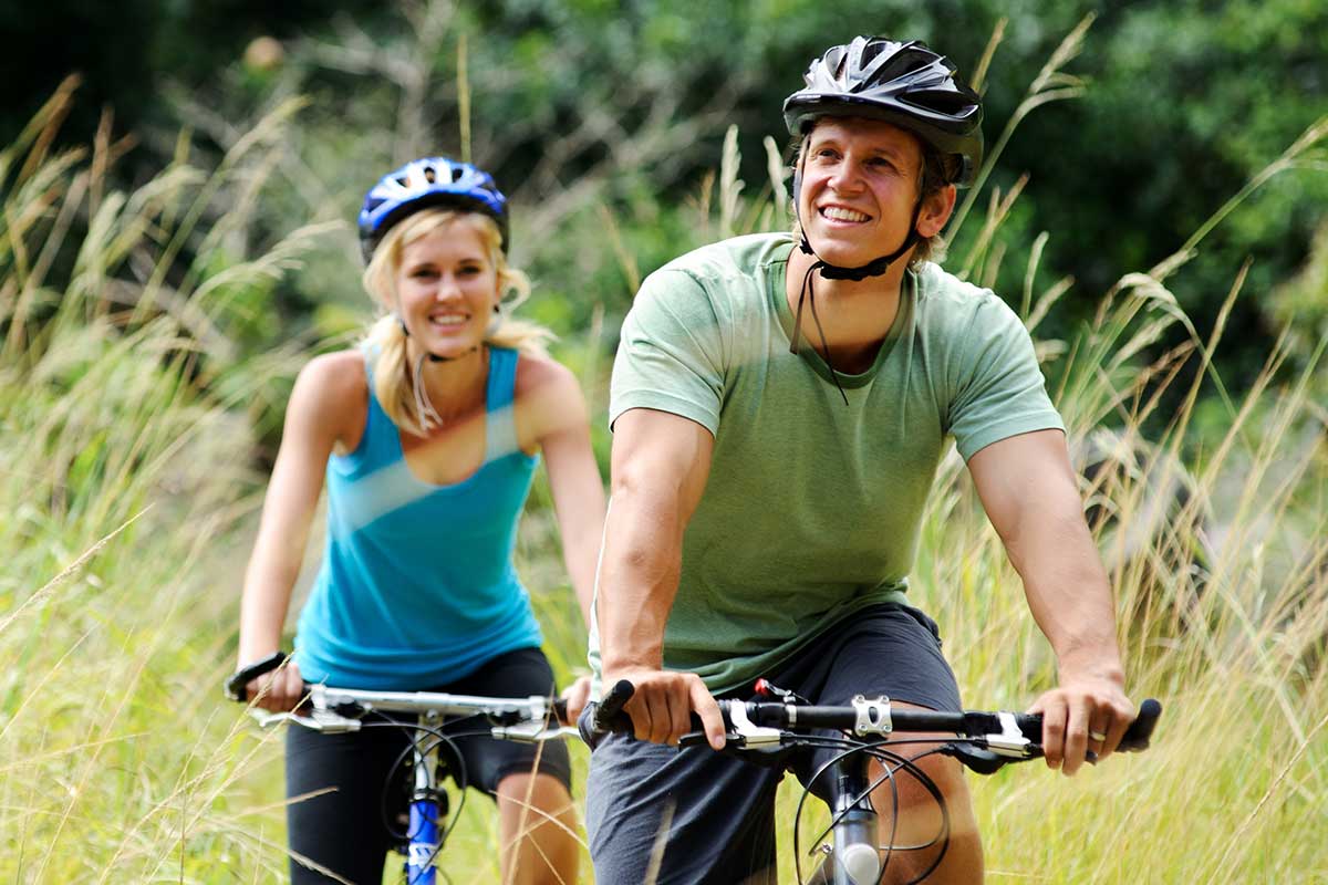 Smiling man and woman riding bikes on the trail